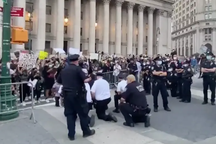 A photo of Lt. Robert Cattani and other officers kneeling at a protest on May 31st, 2020